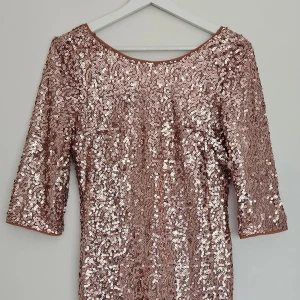Paljettklänning i roséguld  - Kort paljettklänning från Forever 21 i roséguld. Djup v-ringning i ryggen med dragkedja bak och halvlånga ärmar. Figurnära passform. Använt få gånger , mycket bra skick. Storlek S 