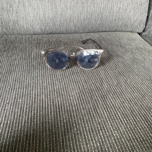Genomskinliga solglasögon med svarta glas - Snygga solglasögon med transparent båge och svarta, runda glas. Klassisk och stilren modell som passar till de flesta outfits. Bågarna är i plast och har en modern vibe med sin genomskinliga look. Kan vara lite sne men de är fina på