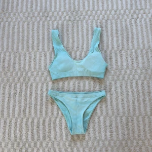 Ljusblå ribbad bikini  - Superfin ljusblå bikini från Cubus med ribbad struktur. Topp med breda axelband och rundad urringning, matchande trosa med klassisk passform. Perfekt för strandhäng och pooldagar. Säljs som set men olika storlekar på topp och trosa. 