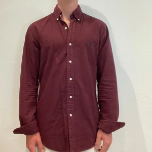Vinröd Ralph Lauren Skjorta  - Vinröd Ralph lauren skjorta || Storlek M (Slim Fit) || Skjortan är i bra skick, däremot urtvättad || Mitt pris 499kr || Modellen på bilden är 170cm och väger 62kg || Tveka inte på att höra av dig vid frågor eller funderingar 