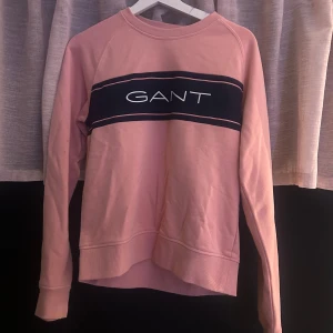 Rosa sweatshirt från GANT - Säljer en rosa sweatshirt från GANT med svart och vit logga över bröstet. Inte använd nån gång 