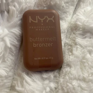 NYX Buttermelt Bronzer Butta Biscuit - NYX Buttermelt Bronzer i färgen Butta Biscuit, en krämig bronzer i medium gyllene ton. Kommer i en smidig brun plastförpackning på 5g, perfekt att ha med i väskan. Ger en naturlig solkysst look och smälter lätt in i huden. Helt ny aldrig andvänd
