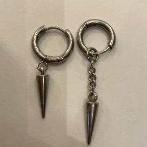 Silvriga örhängen - Säljer dessa örhängen där ena kedjan är lite längre. De är i rostfritt stål och nitarna går att ta av ur ringen.