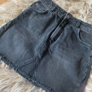 Svart jeanskjol  - Snygg svart jeanskjol med rå, fransig nederkant och klassiska fickor både fram och bak. Köpte på vinted men tyvärr passade inte den mig