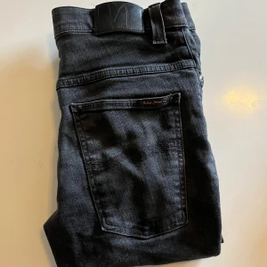 Svarta jeans från Nudie Jeans, 34/32 - Säljer ett par svarta jeans från Nudie Jeans i storlek 34/32 men sitter mer som 30/32 pga modellen som är Skinny lin! Riktigt goa och bekväma jeans till vardagen. Inga defekter eller annat!