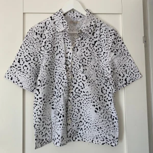 Leopardmönstrad skjorta Gina Tricot - Kortärmad skjorta från Gina Tricot i vitt med svart leopardmönster. I storlek 36. Aldrig använd. 