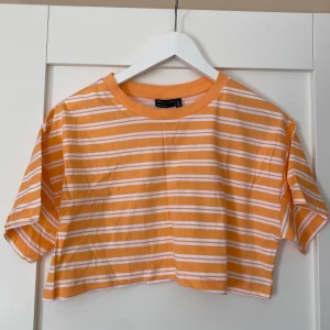 Randig croppad topp från ASOS DESIGN - Croppad topp från ASOS DESIGN i orange och vitt med horisontella ränder. I storlek 36. Aldrig använd. 