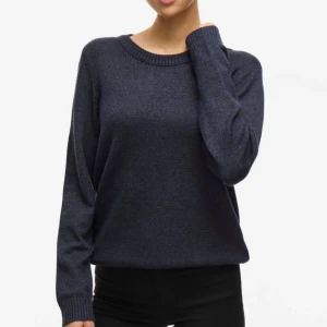 Mörkblå stickad tröja med rund hals - GARDEROBSRENSNING! Enkel och stilren mörkblå stickad tröja med rund halsringning och långa ärmar. Tröjan har ribbade muddar vid ärmslut och nederkant, vilket ger en snygg och klassisk look. Perfekt att matcha med jeans eller kjol för en chill vibe.