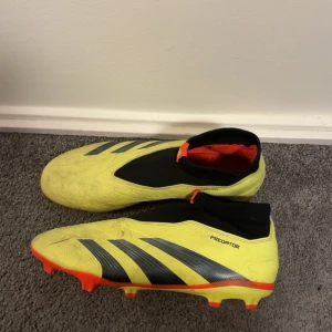 Adidas Predator  - Säljer ett par Adidas Predator fotbollsskor i en riktigt fet gul färg med svarta och röda detaljer. Skorna har en strumpliknande svart krage, silvriga ränder och röda dobbar undertill. Ovandelen är i syntetmaterial och designen är modern och sportig. Gör en ren och exklusiv tvätt innan de postas:)