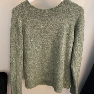Grön stickad tröja från Vero Moda - Mysig ljusgrön stickad tröja från Vero Moda med rund halsringning och ribbade muddar. Tröjan har en enkel och stilren design, perfekt att slänga på sig när det är kyligt ute. Långärmad och i mjukt material som känns skönt mot huden.