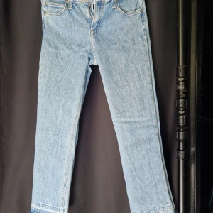 Lee Cropped Bootcut Jeans ljusblå W26 - Snygga ljusblå jeans från Lee i modellen Cropped Bootcut. Jeansen har råa, fransiga benslut och klassisk femficksdesign. Tillverkade i stretchig denim med 98% bomull och 2% elastan för skön passform. Perfekta för en avslappnad och trendig look.