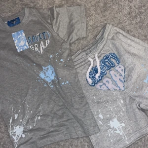 Gravity Grab grå t-shirt med tryck - TikTok kända märken! Grå t-shirt från Gravity Grab med coolt blått och vitt splash-tryck framtill och texten 'SPLASH THE WORLD' på ryggen. Broderad logga på bröstet och streetinspirerad design. Skön passform och tillverkad i mjuk bomull. Säljer 1 för 600 men om man vill köpa båda tillsammans blir det 1000kr! Dem är ej använda! 