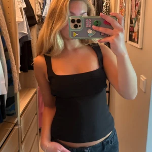 Svart topp från Zara - Snygg svart topp Zara med breda axelband och fyrkantig urringning. Toppen är figurnära. Stretchigt material.