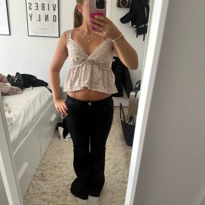 Blommig croppad linnetopp med volang - Supersöt croppad linnetopp med blommigt mönster i rosa och grönt på vit botten. Toppen har breda axelband, v-ringning och volang nedtill. Smockad rygg för extra komfort och luftig känsla. Perfekt för varma dagar och somriga vibes!