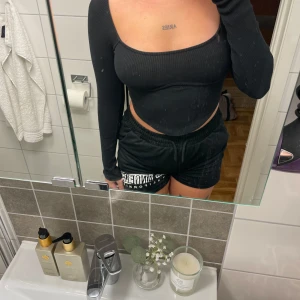 Svart croppad ribbad topp från Nelly - Säljer en svart croppad topp från Nelly med lång ärm och fyrkantig urringning. Toppen är ribbad och sitter tight, perfekt för dig som gillar en stilren och enkel look. Materialet är mjukt och stretchigt för en bekväm passform.