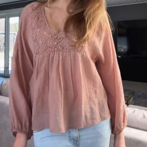 Rosa blus med spetsdetaljer - Supersöt rosa blus med v-ringning och broderade spetsdetaljer framtill. Långärmad modell med avslappnad passform och lätt, luftig känsla. Perfekt till jeans eller kjol! Köpt från Zara och aldrig använd💞pris går att diskutera vid snabb affär💞