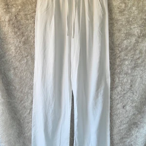 Vita linnebyxor med snörning - Snygga och luftiga vita linnebyxor med resår och snörning i midjan. Byxorna har raka ben, sidfickor fram och två bakfickor. 