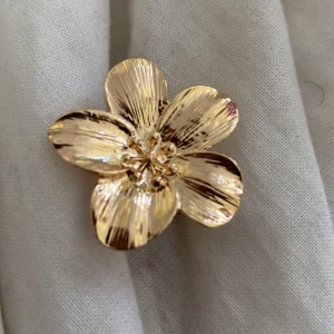 Guldig blomring med fem blad - Snygg och iögonfallande ring i guldtonad metall formad som en stor blomma med fem blad. Blomman har fina detaljer och en glansig finish som verkligen poppar. Perfekt för dig som vill ha ett statement piece på fingret.