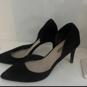 Svarta pumps med spetsig tå - Stilrena svarta pumps från Nelly Shoes i mocka med spetsig tå och smal klack. Snyggt minimalistisk design som ger en elegant siluett. Perfekta för dig som gillar klassiska och trendiga skor med en modern touch.