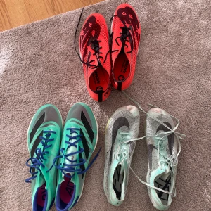 Tre par spiksor Nike & New Balance & adidas - Säljer tre par spikskor ett par neonröda New Balance med svart snörning och mesh-överdel, ett par turkosa Nike med blå snörning och svarta detaljer, samt ett par ljusgröna Nike med vit mesh och grå swoosh. Perfekta för dig som gillar att springa snabbt och snyggt. För fler bilder är det bara att höra av sig. Storlekar är mellan 44-45. Priset på skorna skriver jag privat. 