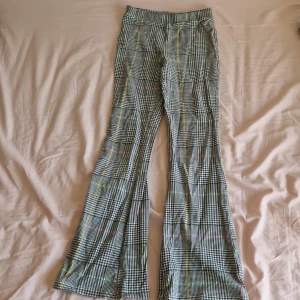 Rudiga utsvängda byxor - trändiga & bekväma  -    Snygga rutiga utsvängda byxor i mjukt och stretchigt material. Perfekta för både vardag och fest. Använda få gånger och i mycket bra skick. Färg: Svart, vit och grön rutig Material: Stretchig polyesterblandning  Tvättade och redo att användas direkt.  