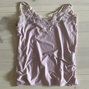 Ljusrosa linnetopp med spets från Amisu - Supersöt ljusrosa linnetopp från Amisu med tunna axelband och v-ringning dekorerad med spets.