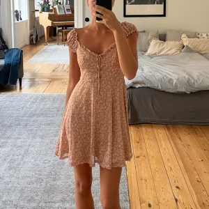 Sundress från Lush - Supersöt kortklänning från Lush i ljusrosa med små vita blommar. 