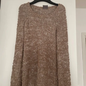 Beige stickad tröja med paljetter - Säljer en beige stickad tröja med lång ärm och rund hals. Tröjan har ett chunky garn med insydda små paljetter som ger lite extra glans. Perfekt för dig som gillar en mysig och unik look. Passar dig som vill ha något som sticker ut lite i höst och vinter.
