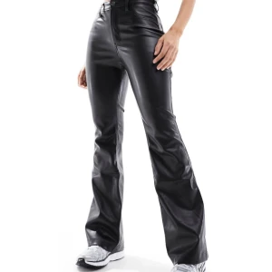 Svarta bootcut byxor i skinnimitation - Obs första 2 bilderna inte mina!Snygga svarta byxor i skinnimitation med hög midja och bootcut-ben. De har klassiska fickor bak och fram, samt en figurnära passform upptill som blir vidare nedtill. Perfekta för dig som vill sticka ut med en edgy look. Aldrig använda. Byxor från Hollister i imitationsläder / Lack. Mjukt material inuti. Utsvängda. Långa och fina på mig som är 168cm. OBS W25. Jätte fina på!