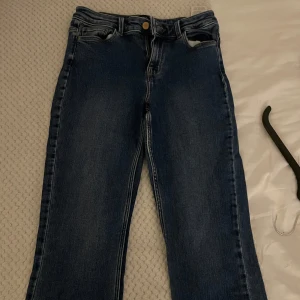 Mörkblå raka jeans - Snygga mörkblå jeans med klassisk femficksdesign och raka ben. Jeansen har en midjehög passform och stängs med dragkedja och knapp. Perfekta till sneakers eller boots för en chill look.