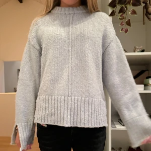 Stickad tröja  - Mysig gråblå stickad tröja med slits på sidorna och armarna. Säljer för att den inte kommer till användning 
