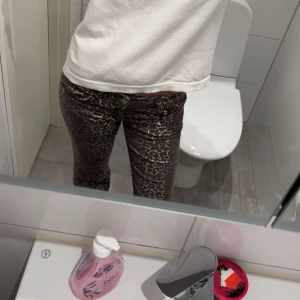 Leopardmönstrade jeansbyxor - Säljer ett par snygga jeansbyxor med leopardmönster i bruna och beige toner. Byxorna har normal passform och klassisk femficksdesign. Perfekta för dig som vill sticka ut lite extra med din outfit.