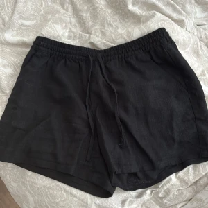 Svarta linneshorts från H&M Divided XS - Svarta shorts i linne från H&M Divided, storlek XS. De har elastisk midja med snörning. Katt finns i hemmet.