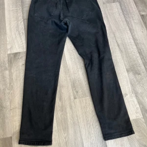 Svarta jeans Lauren Denim 1953 - Snygga svarta jeans från Lauren Denim 1953 i klassisk femficksmodell. Jeansen har rak passform och är tillverkade i mjukt denimtyg. Perfekta för dig som gillar en stilren look med mörka jeans.