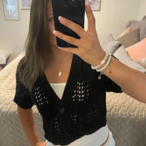 Svart stickad croppad kofta - Säljer denna supersöta svarta stickade koftan med kort ärm och croppad passform då jag inte använder den längre!❣️🙏🏼 pris går att diskutera !