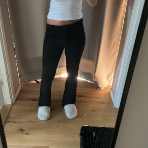 Svarta bootcut byxor - Säljer ett par svarta byxor med bootcut-snitt och låg midja. De har en klassisk look med smal passform upptill och utsvängda ben. Perfekta för dig som gillar en stilren och trendig vibe. Passar till allt och är superenkla att styla.