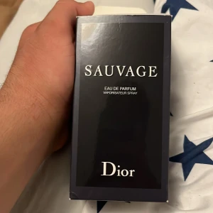 Dior Sauvage Eau de Parfum 100ml - Dior Sauvage Eau de Parfum 100ml med elegant svart och mörkblå glasflaska. Doften är maskulin och fräsch, levereras i originalförpackning med stilren svart design och tydlig logga. Perfekt för dig som gillar exklusiva och moderna parfymer.