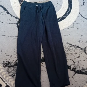 Svarta mjukisbyxor med snörning - Svarta mjukisbyxor från 157 med bred resår i midjan och snörning. Byxorna har raka ben och två stora fickor framtill. Perfekta för chill dagar eller när du vill vara extra bekväm.