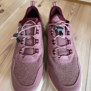 Rosa ECCO MX sneakers strl 42 - Säljer ett par ECCO MX skor i en snygg rosa och vinröd färg. Skorna har en grov vit sula och en smart snörning. Perfekt för dig som gillar sportig stil och vill ha bekväma skor med cool design. Skorna är i mycket bra skick och  endast andvända ett par gånger. Har inte plats för skorna längre och därför säljer jag dem till ett bra pris.