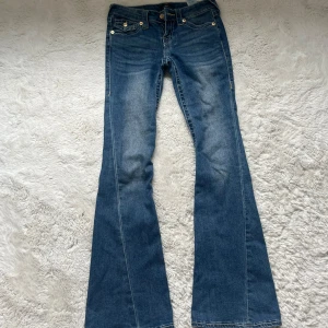 True Religion Joey Low Rise Flare Jeans - Säljer dessa blåa true religion jeans med gula detaljer i storlek 23 och modell joey. På ena enden av benet har det gått sönder lite men det är inget man tänker på (ni kan ser det på bilden 5). Säljer på grund av att dem kommer inte till användning längre och pris kan alltid diskuteras 💕 (original pris var 1400).