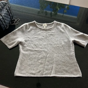 Grå kashmirtröja med kort ärm - Supermjuk grå tröja i kashmir med korta ärmar och rund hals. Enkel och clean design som är lätt att matcha med allt. Perfekt för dig som gillar stilrena och sköna plagg. Ribbstickade detaljer vid hals, ärmslut och nederkant ger en snygg finish. Jätte mysig till hösten 😌🍂