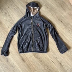 Grå kofta med broderi - Mörk grå kofta med blommor på bröstet och baktil är det fåglar och blommor. Den är i ett otroligt skönt material och är väldigt mysig att ha på kvällarna. Den har två fickor framtil och en guldig dragkedja. Den är från Lindex men är köpt för länge sedan. Kvaliten är väldigt bra och den har inga synliga defekter. Skriv till mig vid frågor. 