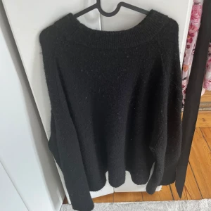 Svart stickad tröja från Ginatricot - Mysig svart stickad tröja från Ginatricot i storlek M. Tröjan har en rundad halsringning och långa ärmar, perfekt för att hålla dig varm under kyliga dagar. Enkel och stilren design som funkar till många olika outfits.