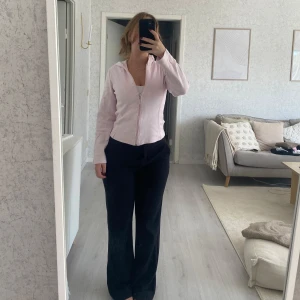 Ljusrosa zip-hoodie med huva - Säljer en ljusrosa hoodie med dragkedja och huva. Jackan är figursydd med lång ärm och har en enkel, clean look. Perfekt att slänga på sig över ett linne. Materialet känns mjukt och skönt, troligtvis bomull eller polyester. Storlek 38 men känns mer som en 36.