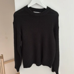 Svart stickad tröja från NA-KD - En svart stickad tröja från NA-KD med rund halsringning och ribbade muddar vid ärmslut och nederkant. Tröjan har en klassisk, lite loose passform och är perfekt för lager-på-lager. Enkel och stilren design som funkar till allt.