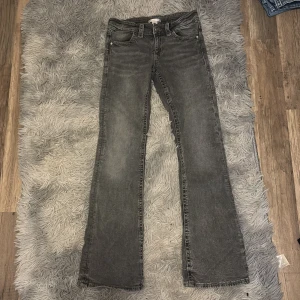 Grå bootcut jeans från Gina Tricot - Snygga grå jeans från Gina Tricot i bootcut-modell. Jeansen har coola detaljer med flätad söm på bakfickorna och klassisk femficksdesign. Materialet är jeans och färgen är tvättad grå, perfekt för en chill och trendig look.