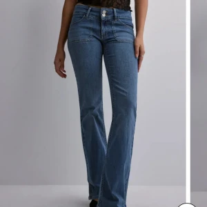 Blå bootcut jeans med låg midja - Säljer ett par snygga bootcut jeans med låg midja från Nelly, jeansen är helt slutsålda på hemsidan. Jeansen är i storlek 34 och endast använda ett fåtal gånger. Köpta för 699 kr. 