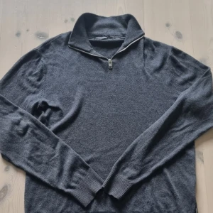 Mörkgrå half zip-tröja Jack & Jones - Mörkgrå långärmad tröja från Jack & Jones med half zip-dragkedja i halsen. Tröjan har ribbade muddar och är tillverkad i mjukt stickat material. Perfekt för lager-på-lager och chill stil. Priset är inte hugit i sten! 