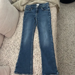 Blå bootcut jeans från Gina Tricot - Snygga blå jeans från Gina Tricot i klassisk bootcut-modell. Jeansen har fem fickor, normal passform och är tillverkade i mjukt denimtyg med lite stretch. Perfekta för dig som gillar en tidlös look med lite utsvängda ben.