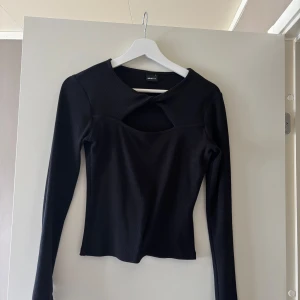 Svart långärmad topp från ginatricot stl S - Svart långärmad topp från Gina Tricot med cut out-detalj vid halsen. Använd 1-2 gr. fint skick. 